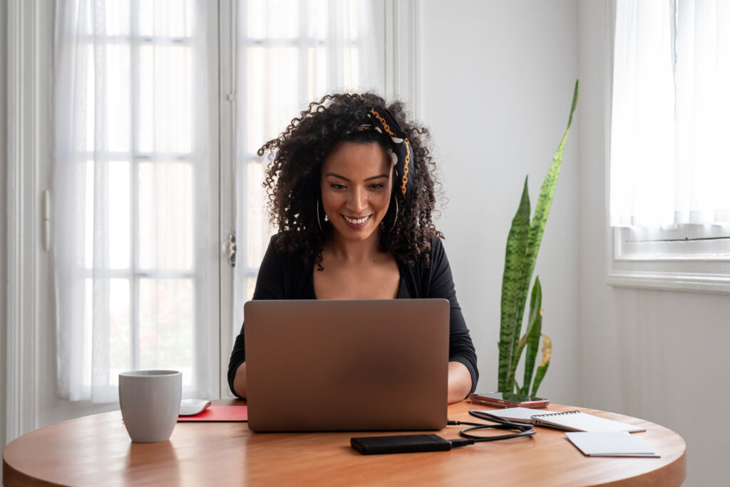 Shot of young latin woman working at home with laptop and documents