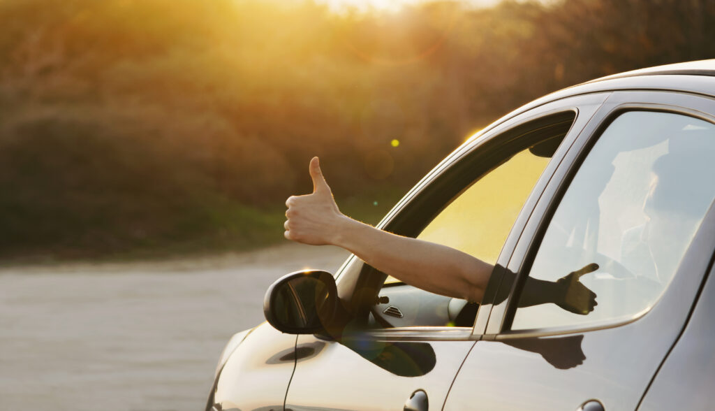 Man showing thumbs up from car window. Vacation and travel concept