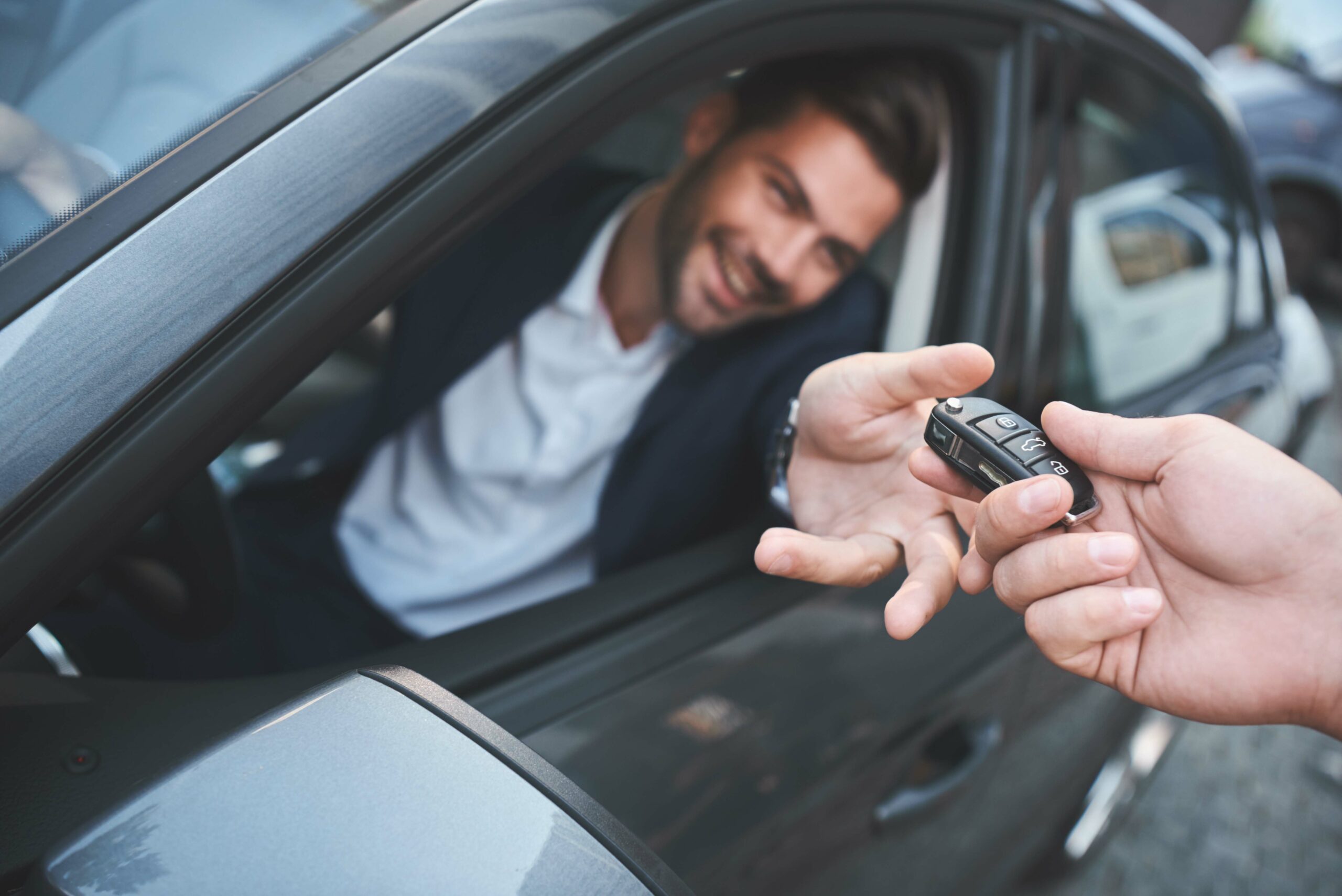 Car dealership.Young man receiving car key from saleswoman.